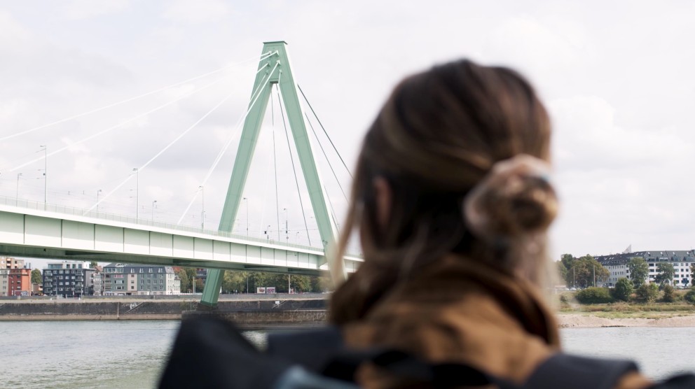 
				Anna stojí u Rýna a dívá se na ocelový most.

			