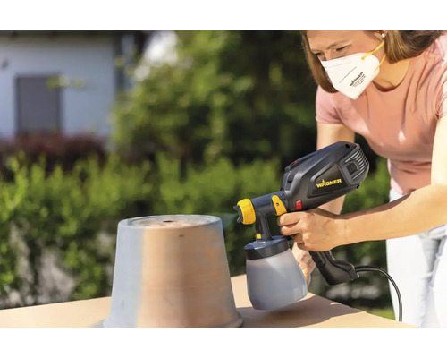 Žena stříká hrnec venku pomocí stříkacího systému