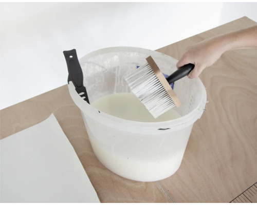 Lepidlo na tapety v kbelíku se štětkou a nožem na tapety