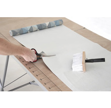 Řezání tapety nůžkami na tapetovacím stole