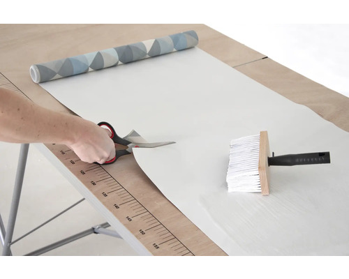 Řezání tapety nůžkami na tapetovacím stole