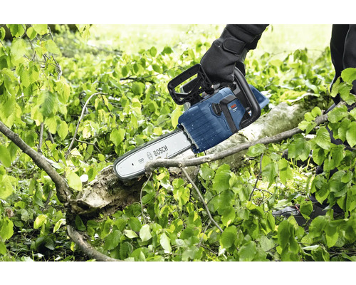 Osoba řeže větev motorovou pilou Bosch.