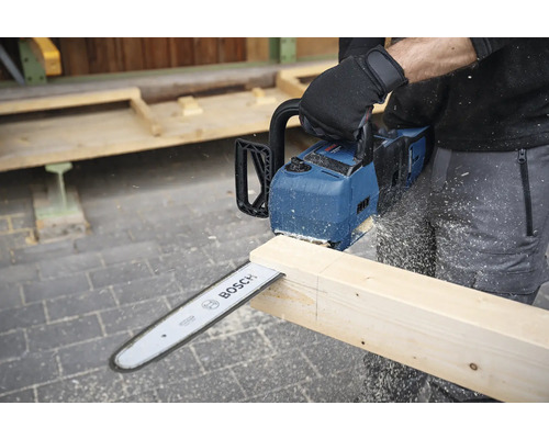 Osoba řeže dřevěnou desku akumulátorovou pilou Bosch.