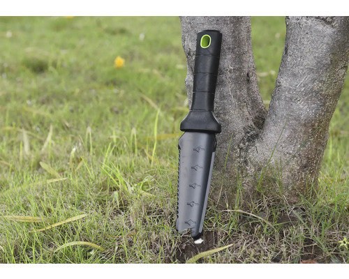 Zahradní nástroj s rukojetí a měřicí stupnicí opřený o strom