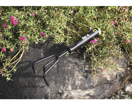 Zahradní kultivátor na kameni mezi rostlinami