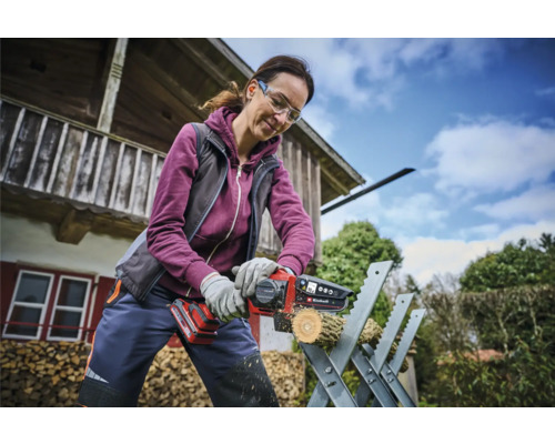 Žena řeže kus dřeva akumulátorovou pilou na kozlíku