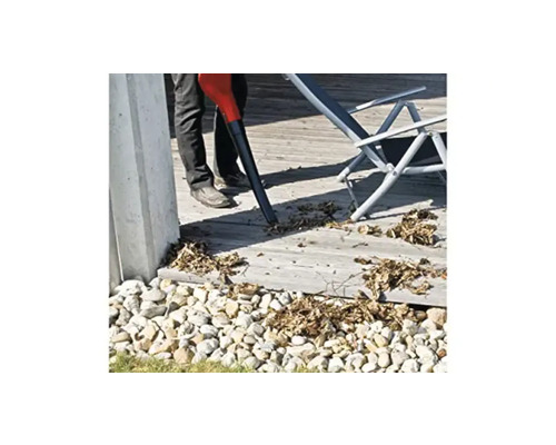 Osoba používá vysavač listí na terase obklopené kameny.