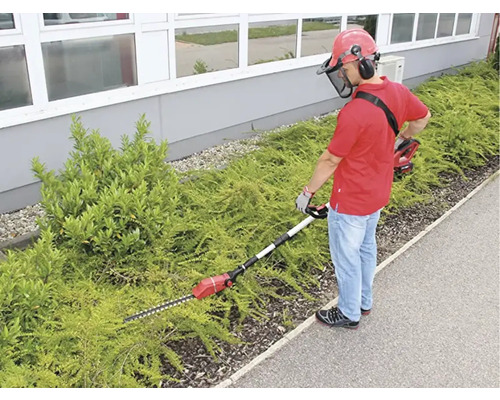 Osoba stříhá živý plot nůžkami na živý plot