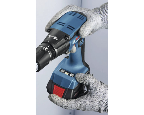 Osoba v rukavicích drží akumulátorový šroubovák na sádrokarton.