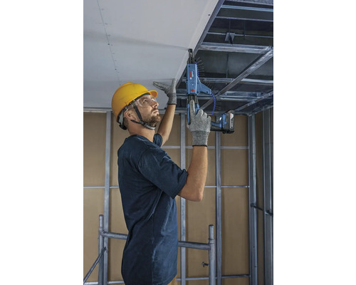 Řemeslník upevňuje stropní desky pomocí šroubováku s podavačem