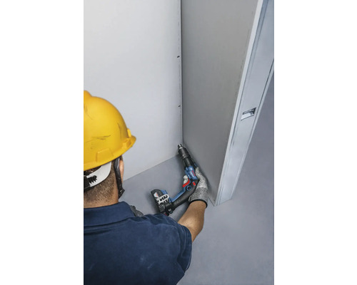 Řemeslník s akumulátorovým šroubovákem při montáži sádrokartonu