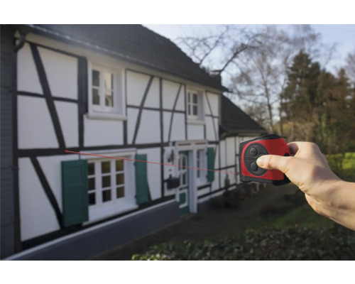 Ruka používá laserový dálkoměr na hrázděném domě