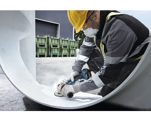 Stavební dělník opracovává trubku úhlovou bruskou