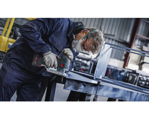 Řemeslník řeže kov přímočarou pilou v dílně.