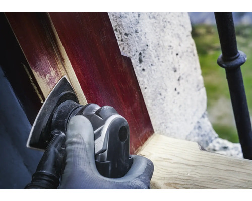 Osoba brousí dřevo pomocí trojúhelníkové brusky.