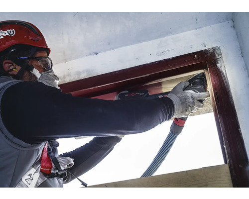 Řemeslník renovuje okenní rám multifunkčním nástrojem