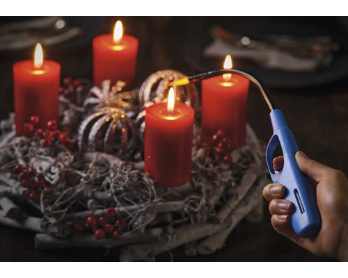 Adventní věnec se čtyřmi hořícími svíčkami a ruka se zapalovačem