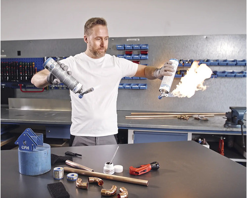 Muž pájí měděné trubky plynovým hořákem