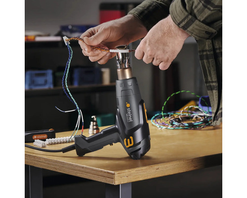 Osoba používá horkovzdušnou pistoli Steinel ke zpracování kabelů.