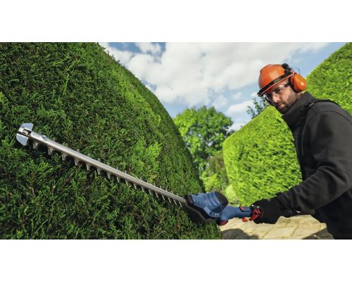 Osoba stříhá živý plot pomocí nůžek na živý plot.