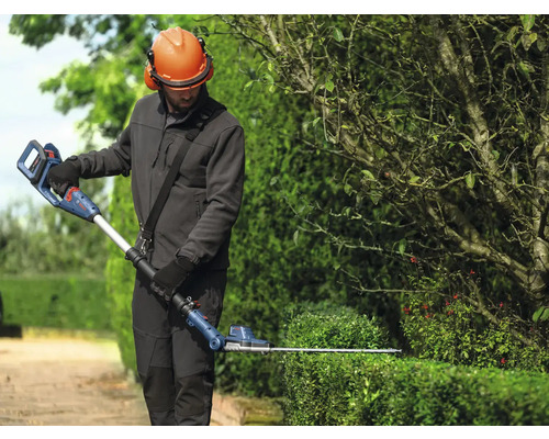 Osoba stříhá živý plot pomocí akumulátorových teleskopických nůžek na živý plot Bosch.