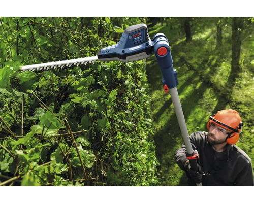 Osoba stříhá živý plot pomocí akumulátorových teleskopických nůžek na živý plot Bosch