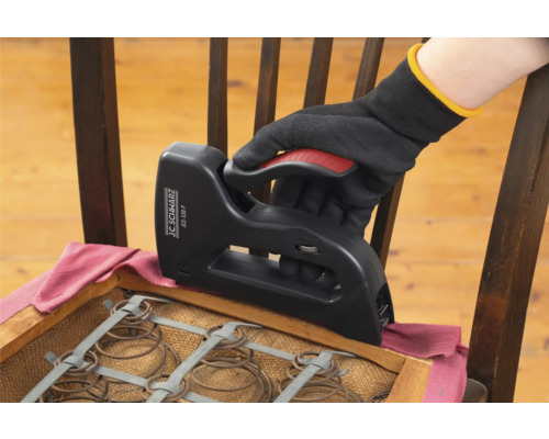 Ruka v rukavici používá sponkovačku k přečalounění židle.