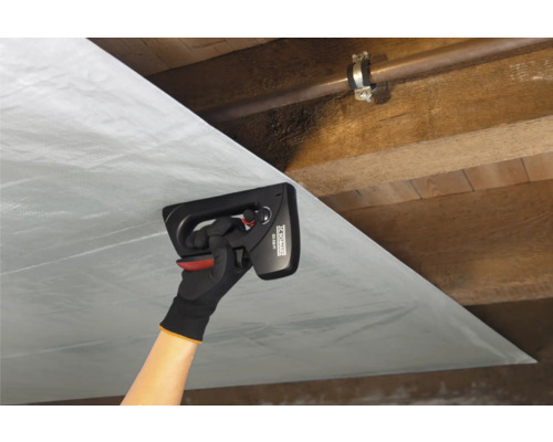 Osoba připevňuje parozábranu ruční sponkovačkou na dřevěný strop.