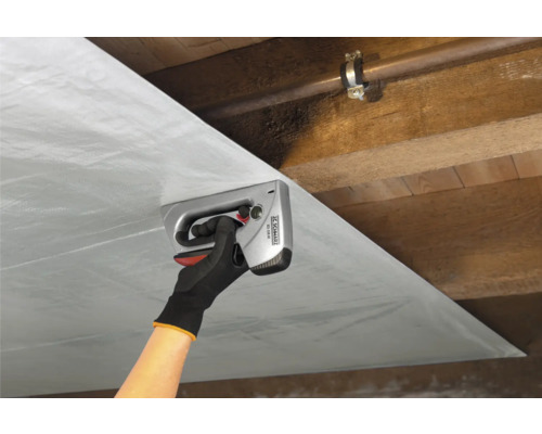 Osoba připevňuje fólii ruční sponkovačkou ke dřevěnému stropu.