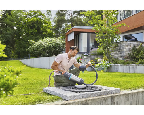 Muž používá sudové čerpadlo Gardena v zahradě k zavlažování zahrady.