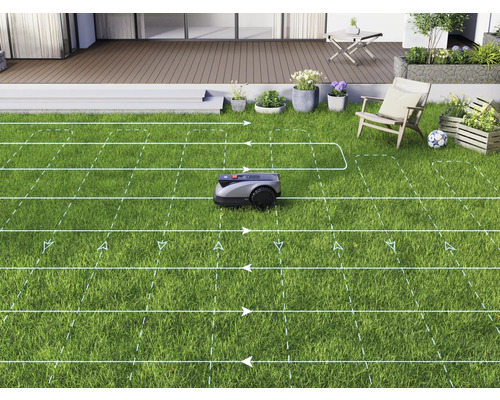 Robotická sekačka seká trávník v zahradě s terasou.