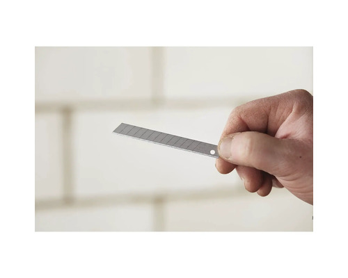 Ruka drží lichoběžníkovou čepel pro ořezávač.