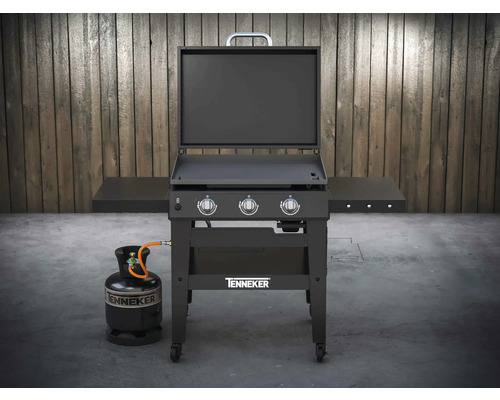 Plynový grilovací vozík Tenneker s plynovou lahví před dřevěnou stěnou
