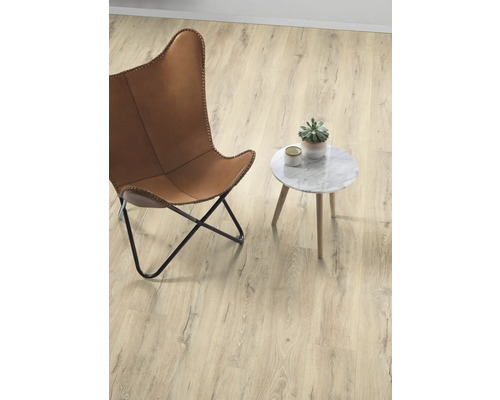 Světlá místnost s křeslem, odkládacím stolkem a hrnkovou rostlinou na dřevěné podlaze