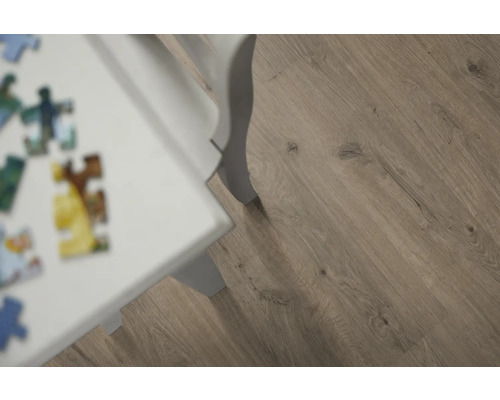 Detail laminátové podlahy s dřevěným vzhledem a bílé nohy stolu