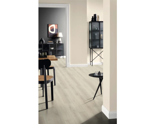 Interiér se světlou laminátovou podlahou, židlemi a dekorativními předměty na stolech a ve skleněné skříni.