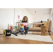 Žena čistí koberec čisticím vysavačem Kärcher ve světlém obývacím pokoji