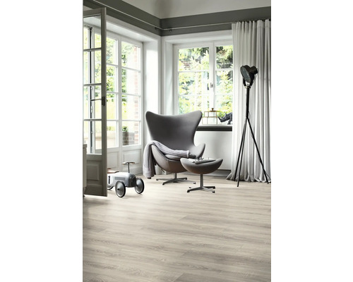 Světlý obývací pokoj s křeslem, stojací lampou, dřevěnou podlahou a velkým oknem