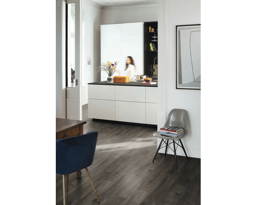 Světlá místnost s kuchyní, jídelním stolem a židlí na tmavé dřevěné podlaze.