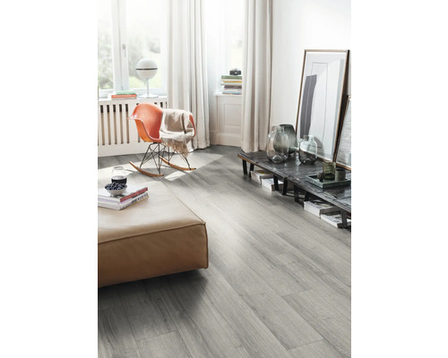 Obývací pokoj s šedou laminátovou podlahou, taburetem a houpacím křeslem.