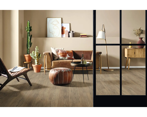 Obývací pokoj s pohovkou, křeslem, stolem, stojací lampou, komodou, dekorací a pokojovými rostlinami na dřevěné podlaze.