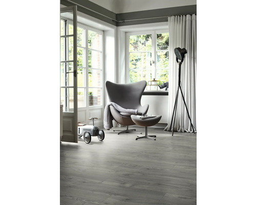 Světlá místnost s moderním křeslem, stojací lampou a šedou vinylovou podlahou s dřevěným vzhledem