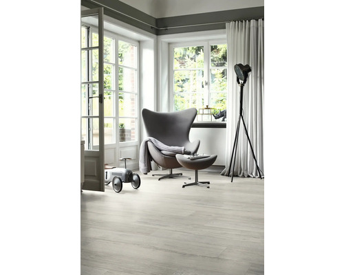 Světlý obývací pokoj s křeslem, lampou na čtení a autíčkem na dřevěné podlaze