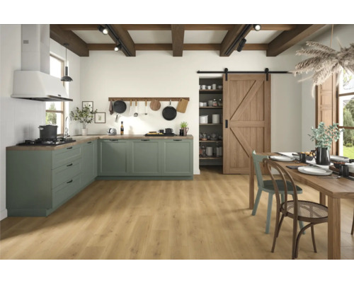 Světlá kuchyně se zelenými skříňkami, dřevěnými trámy a velkým dřevěným stolem