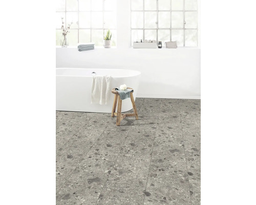 Koupelna s volně stojící vanou, dřevěnou stoličkou a podlahovými dlaždicemi se vzhledem kamene