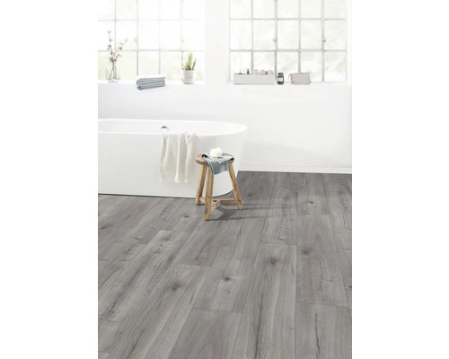 Světlá koupelna s vanou, stoličkou a šedou laminátovou podlahou.