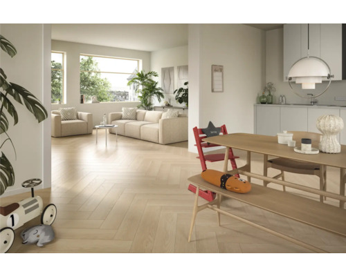 Světlý obývací pokoj s parketovou podlahou se vzorem rybí kosti, pohovkou, křeslem a jídelním stolem s dětskou židlí