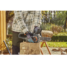 Osoba obsluhuje elektrickou pilu na zahradě.