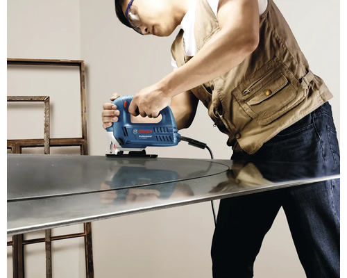 Osoba používá přímočarou pilu značky Bosch Professional k řezání kusu kovu.