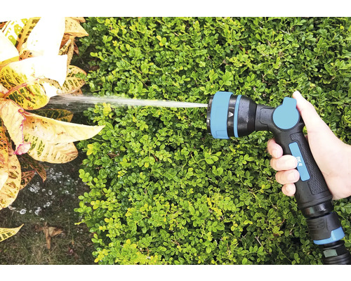 Ruka drží stříkací pistoli zahradní hadice při zavlažování rostlin